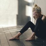 Young teenage girl dancer crying after loss perfomance sits on floor in hall
